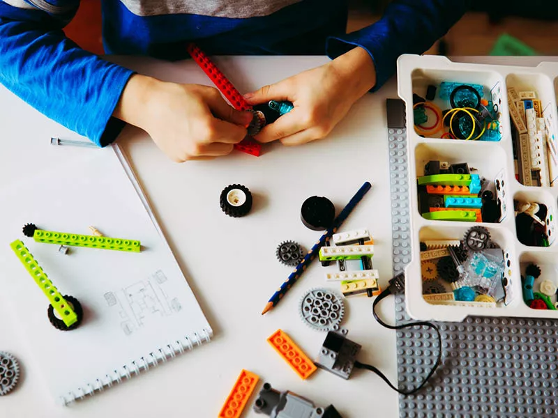 Kids hands working on desk with parts and pieces