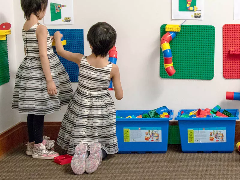 Two children playing with Lego blocks on the wall