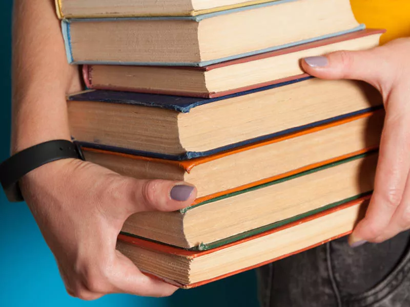 Hands carrying a pile of books